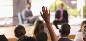 hand in audience raised for a question at a business speaking event