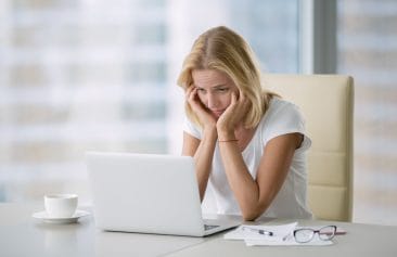 disheartened woman stares at laptop