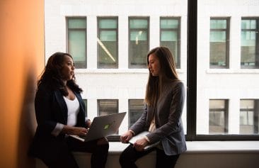 Two Female Coworkers having a conversation by a window